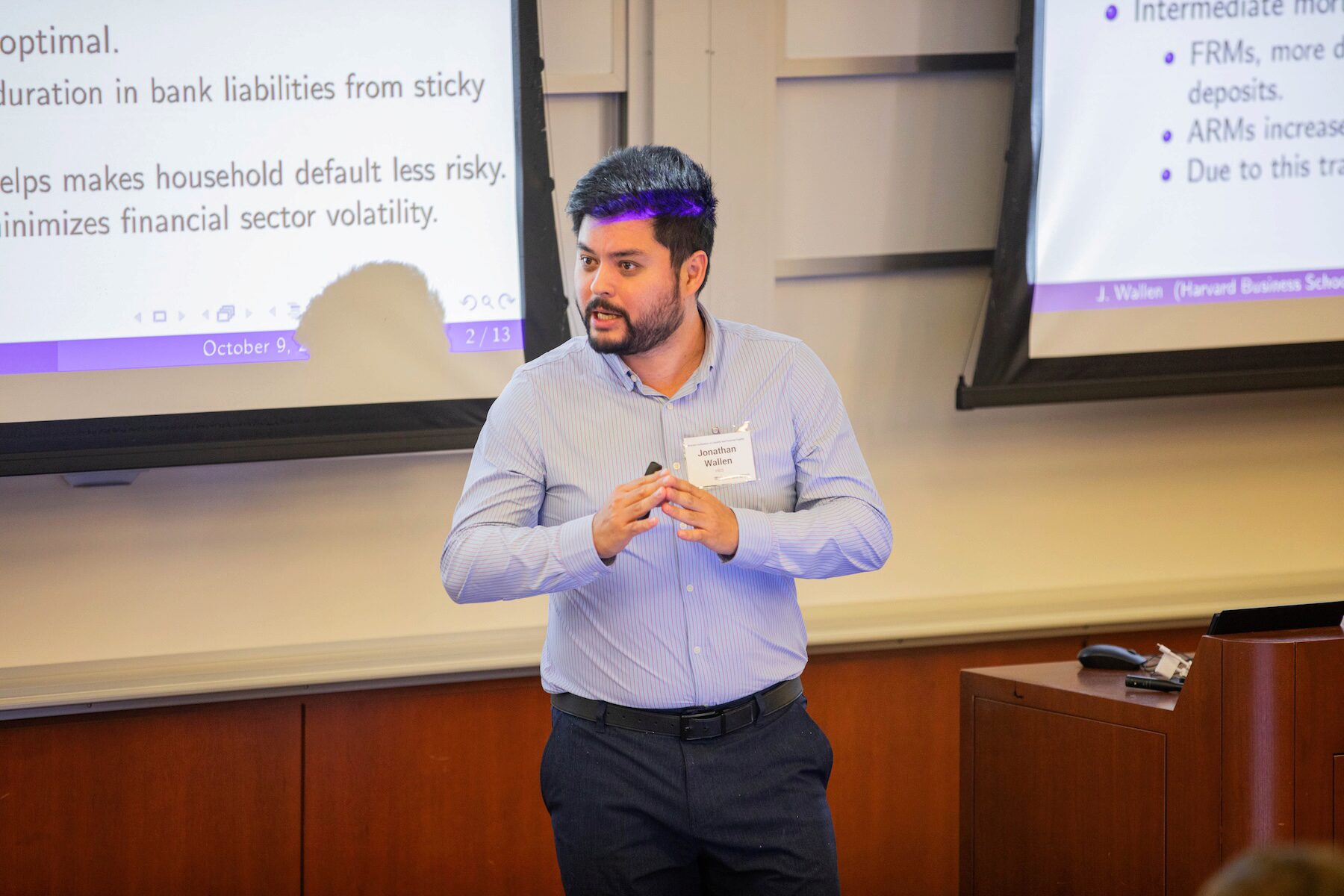 A speaker looks to the viewer's left while presenting at a conference