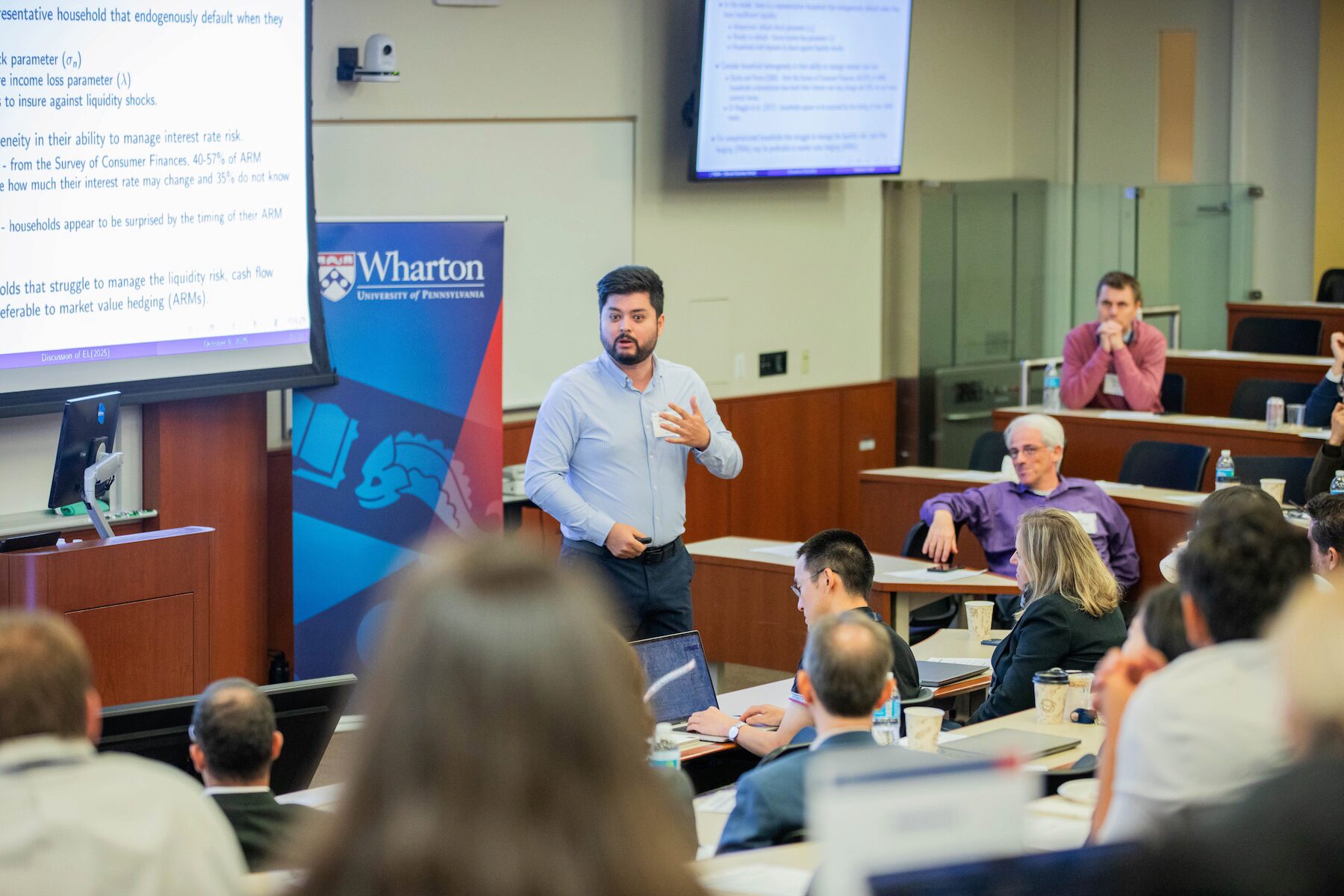 A conference speaker stands in front of an audience