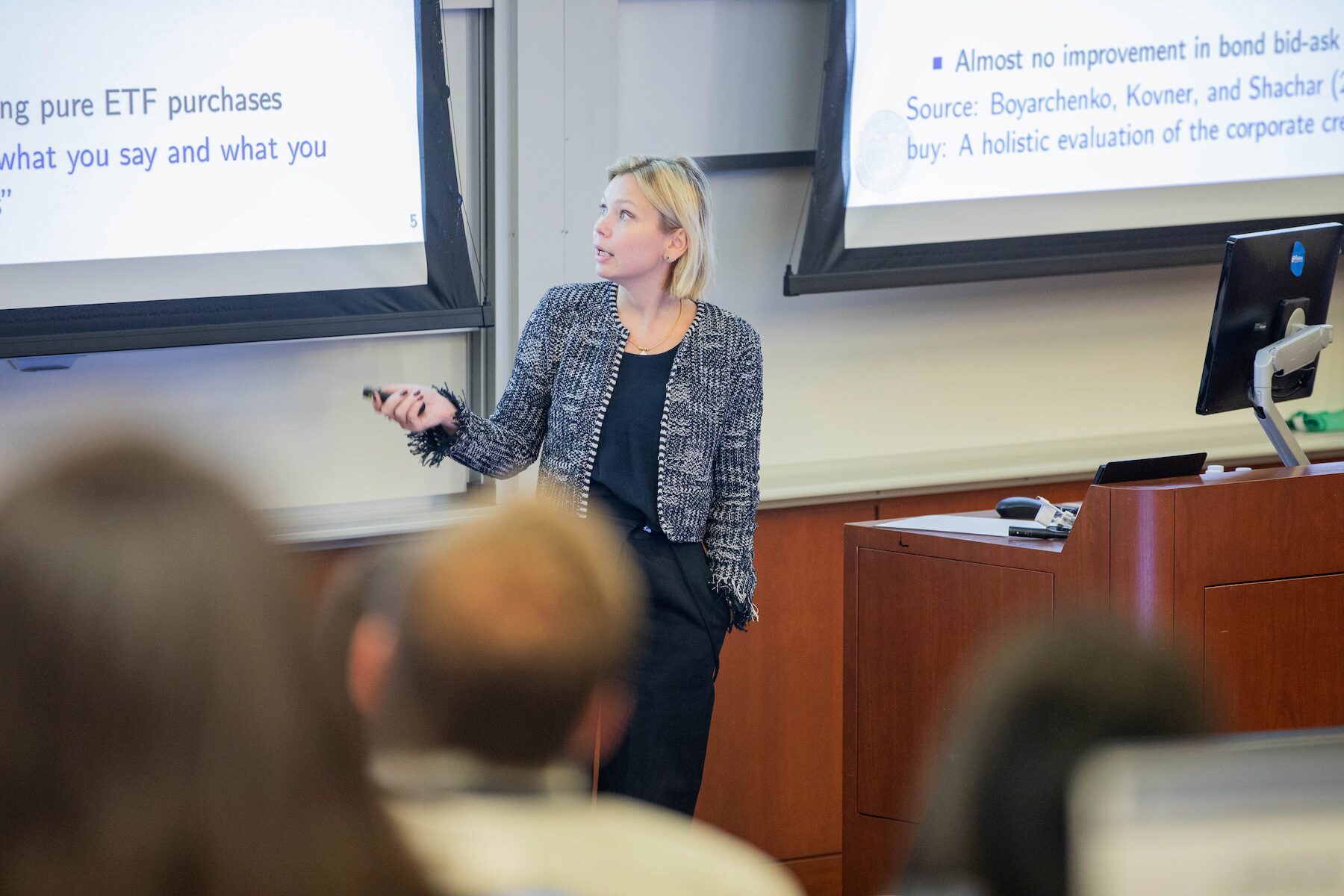 A speaker points a remote clicker toward a projector screen during a presentation